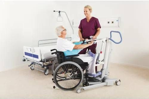 Nurse transferring patient to bed using sit-to-stand lift